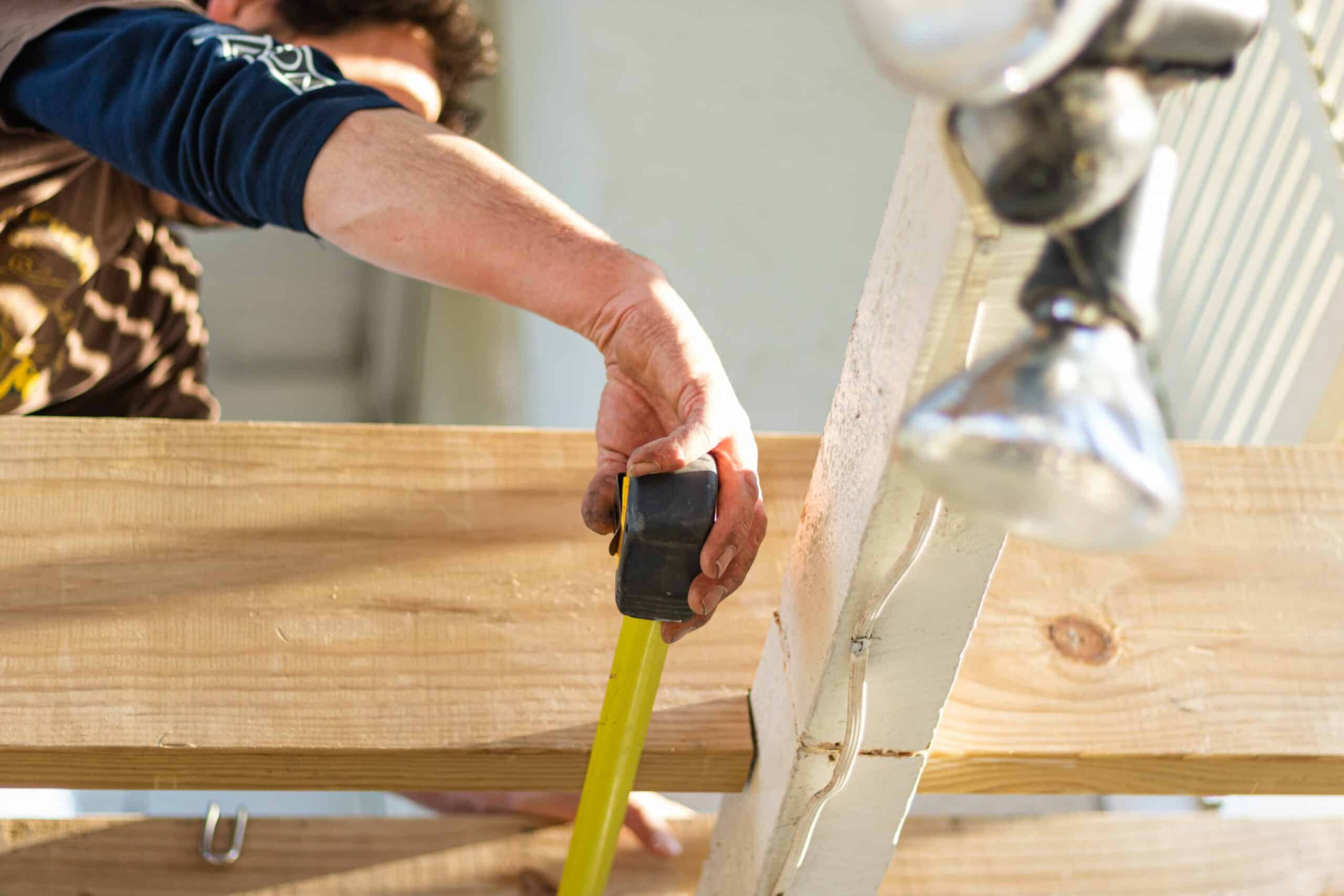 man working on home with tape measure